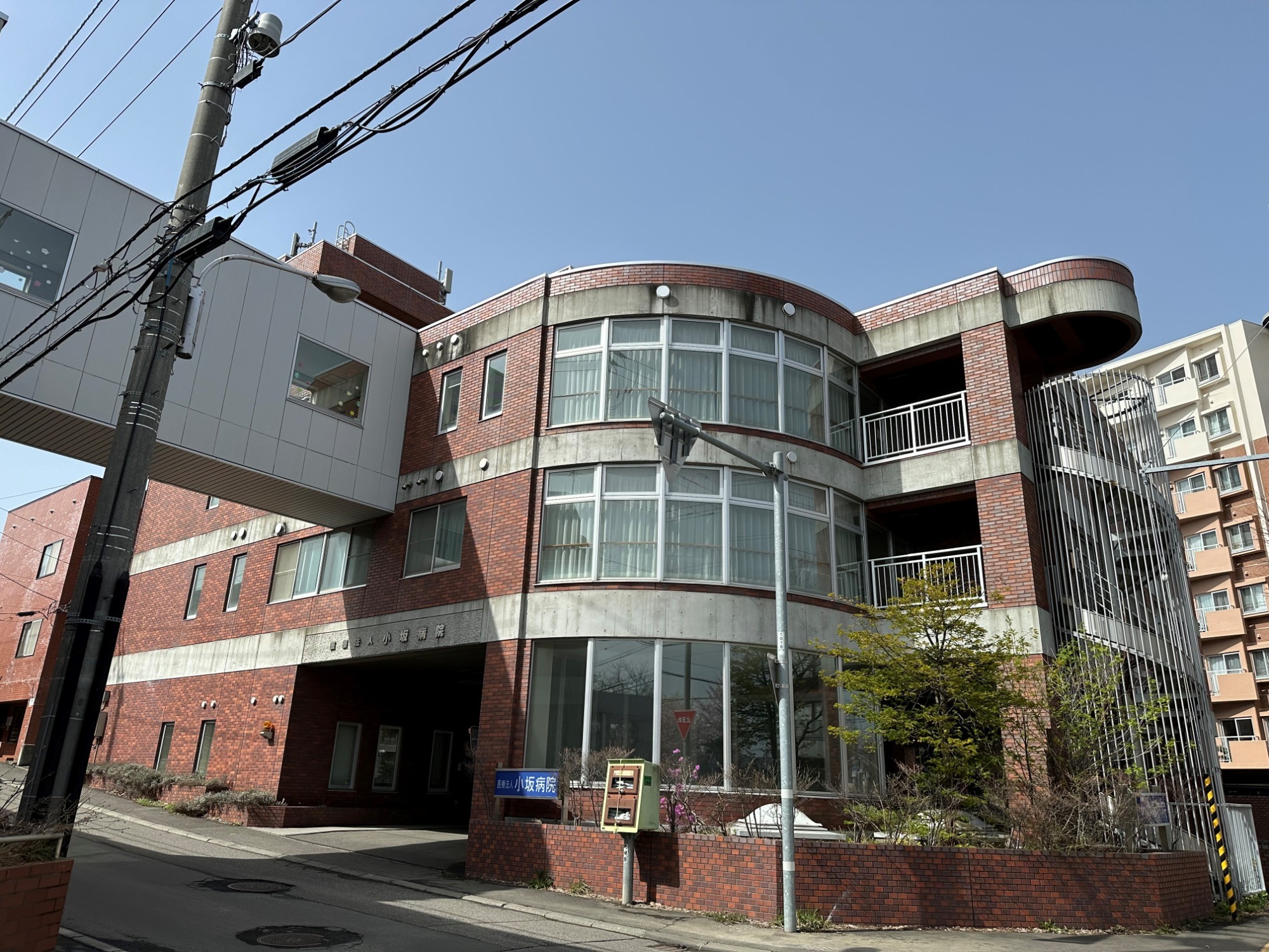 赤レンガと白パネルの混合外観を持つ介護施設の建物。円形バルコニーが特徴的。